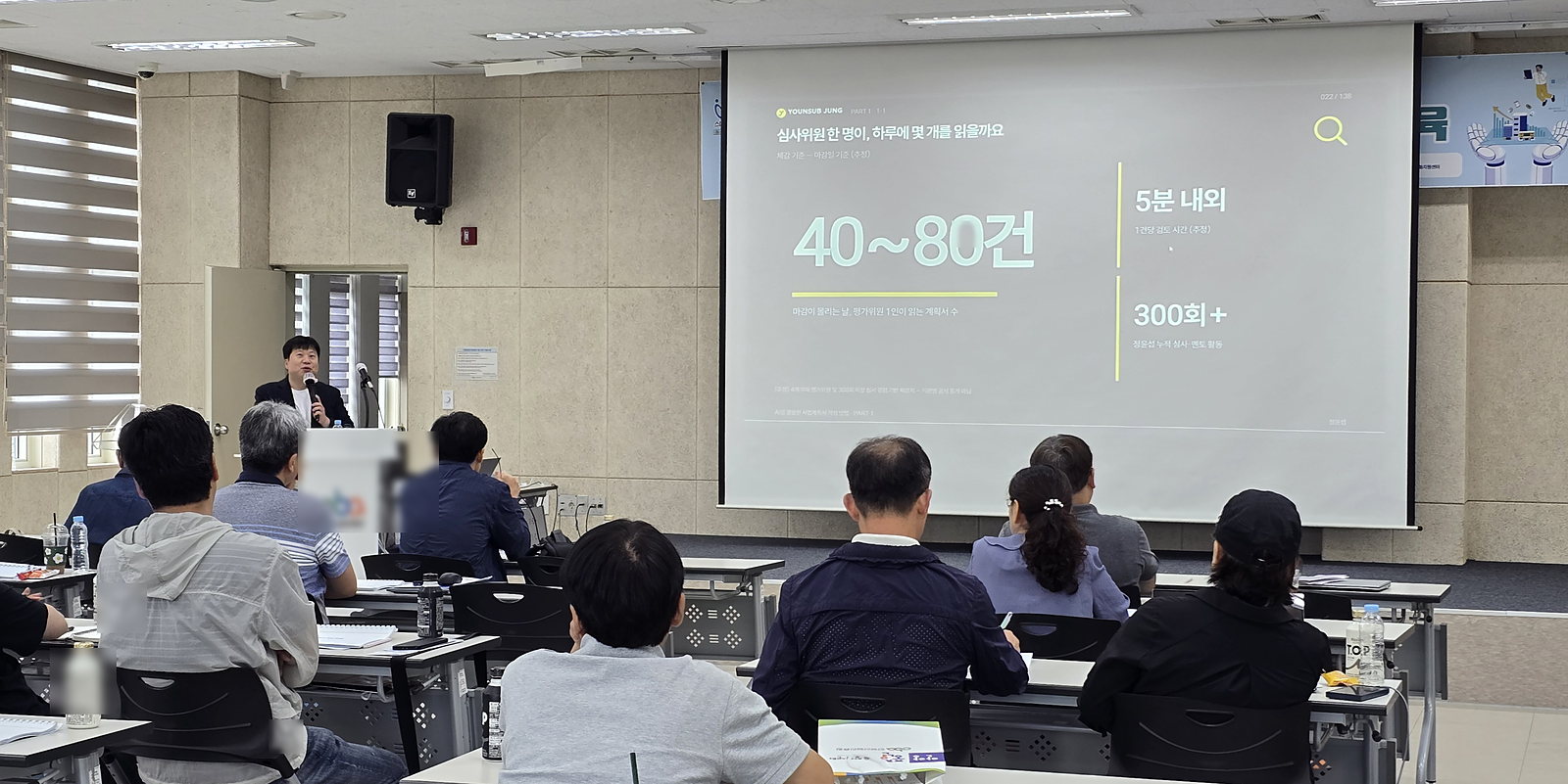 강의실 화면에 「심사위원 한 명이, 하루에 몇 개를 읽을까요」 슬라이드가 떠 있고 40~80건이라는 큰 숫자가 보인다